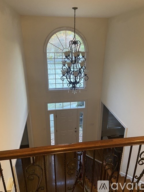 A chandelier hangs in a foyer with a staircase and a door.