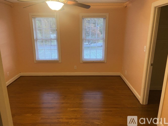 A room with wooden floors and two windows.