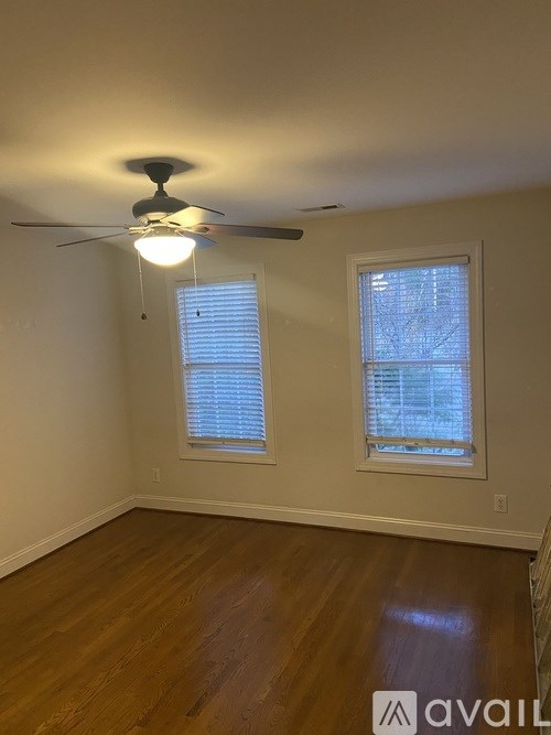 A room with a ceiling fan and two windows.