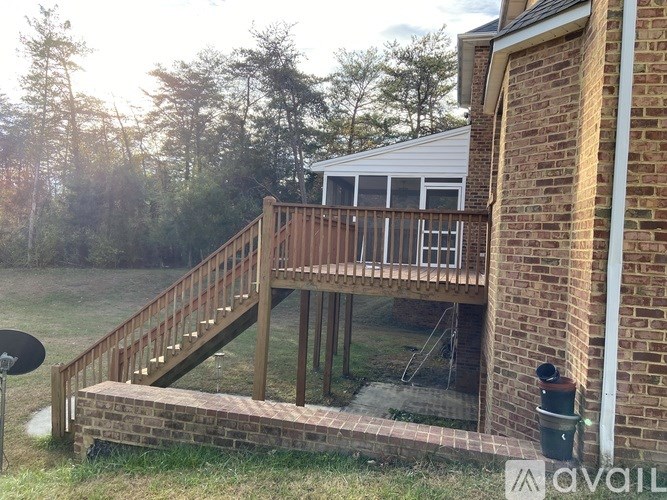A wooden deck with a glass railing and a brick wall.