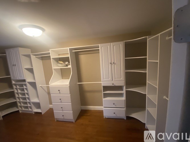 A room with a lot of white cupboards and drawers.