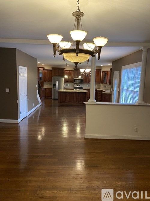 A large open kitchen and living room with wooden floors and a chandelier.