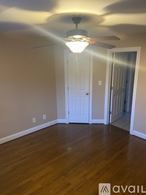 A room with a ceiling fan and wooden flooring.