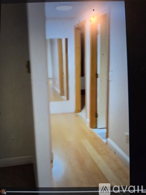 A long hallway with wooden floors and white walls.