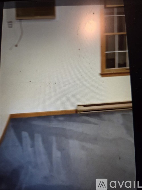 A white wall with a window and a wooden frame at the bottom.