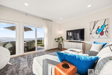A living room with a grey couch and a blue pillow.
