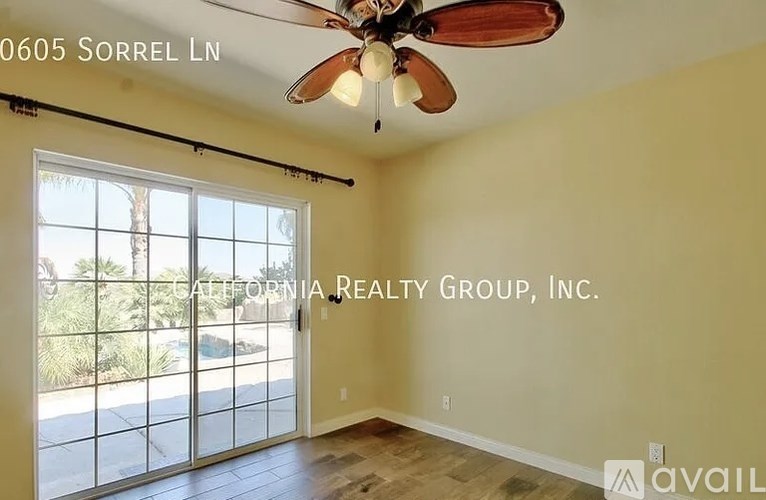 A room with a ceiling fan and a sliding glass door leading outside.