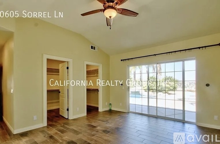 A room with a ceiling fan and sliding glass doors leading to a patio.