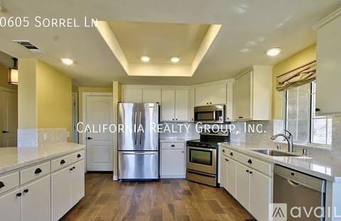 A kitchen with white cabinets and stainless steel appliances is on the market with California Realty Group, Inc.