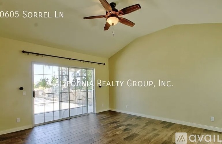 A room with a ceiling fan and sliding glass doors leading to a patio.