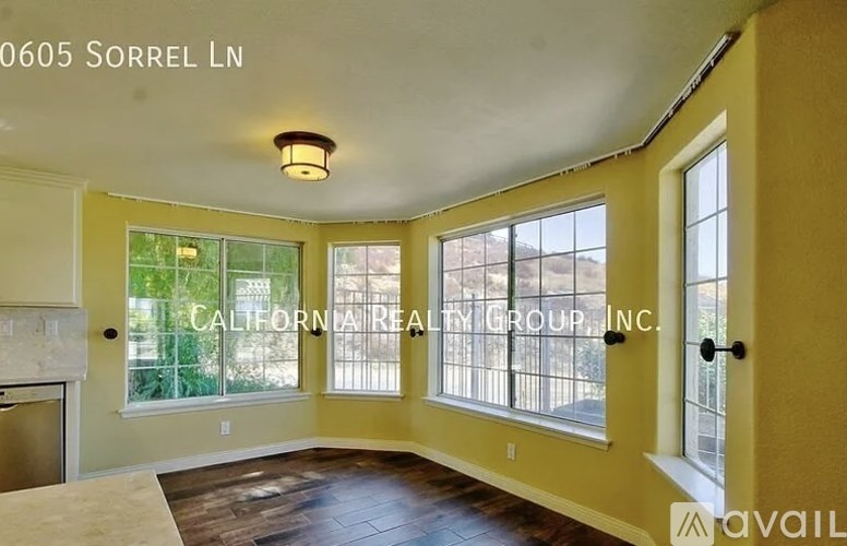 A room with a large window and a view of a fence and trees.