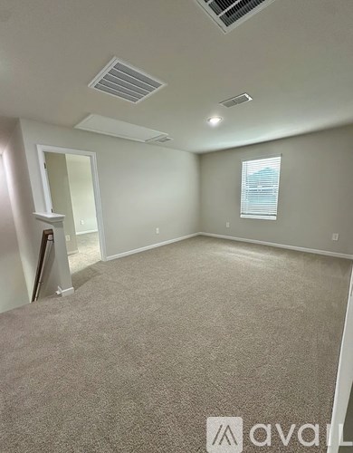 A room with carpeted floor and a window with blinds.
