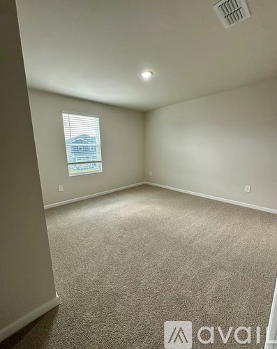 A carpeted room with a window and a ceiling fan.