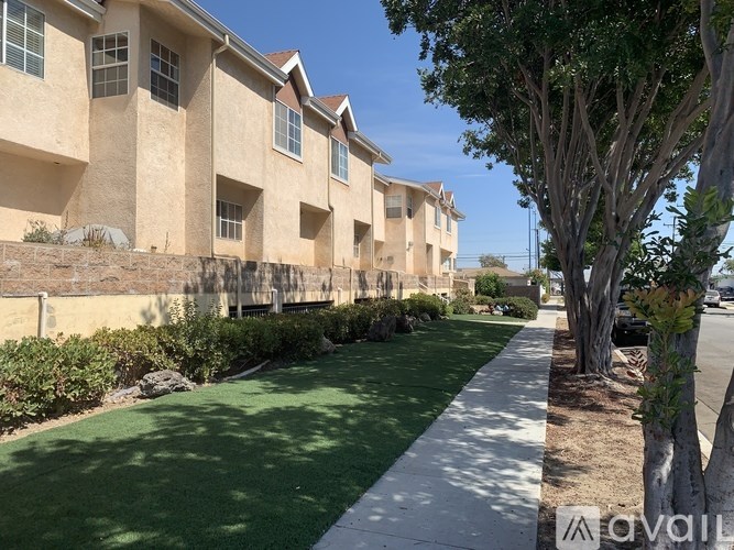 A row of apartment buildings with a sidewalk and green grass.