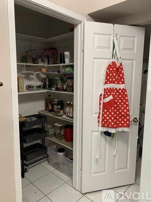 A red and white polka dot apron hanging on a white door.