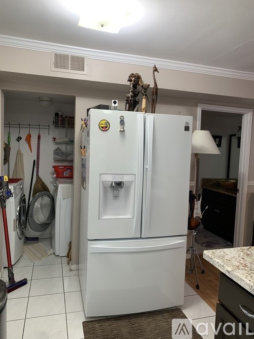 A white fridge with a smiley face magnet on it.