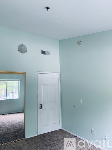 A room with a white door and a carpeted floor.