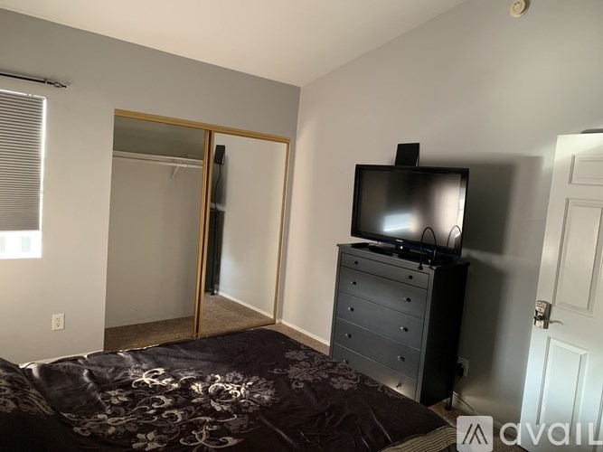 A bedroom with a bed, dresser, and television.
