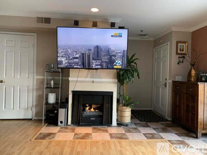 A TV screen in a living room with a fireplace and a plant.