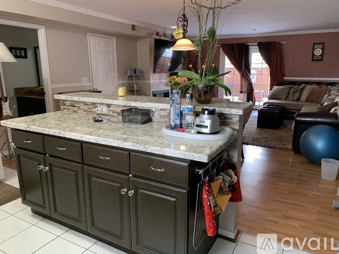 A kitchen with a marble countertop and a dining area with a blue exercise ball.