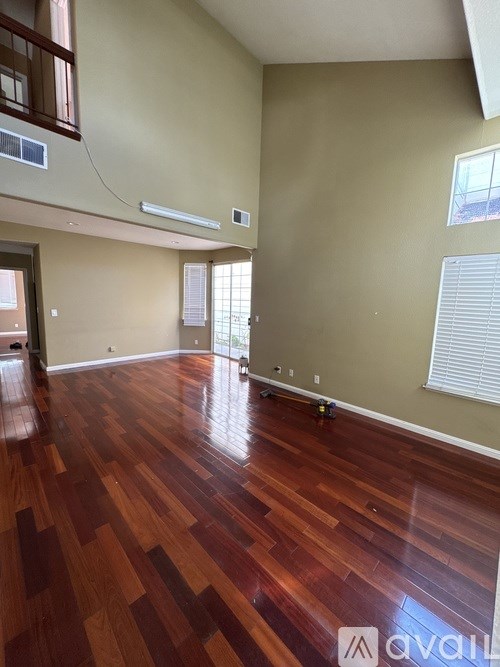 A room with wooden flooring and a window with blinds.