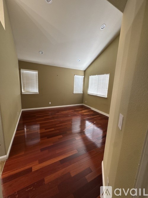 A room with wooden floors and two windows.