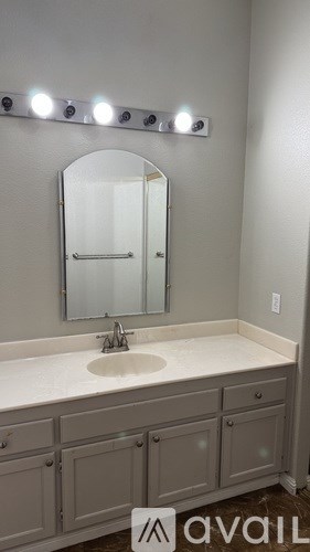 A bathroom with a sink, mirror, and lights.