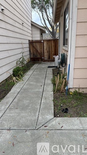 A white house with a wooden fence and a mailbox on the sidewalk.