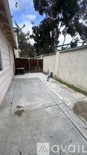 A backyard with a concrete patio and a wooden fence.