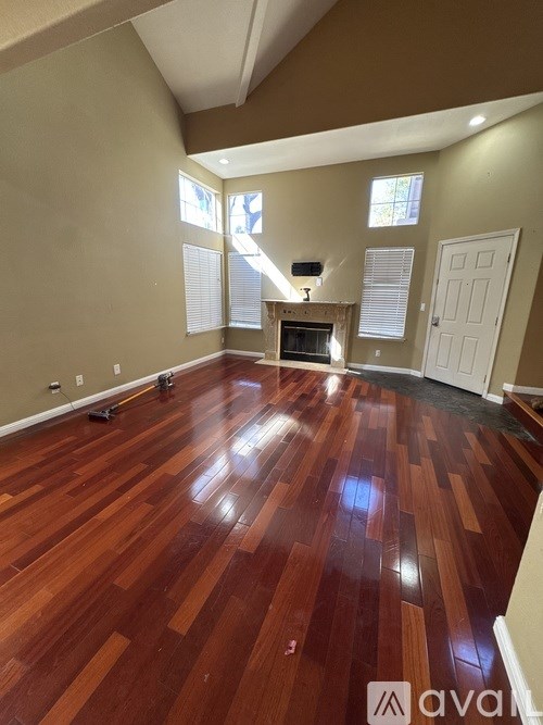 A room with wooden flooring and a television in the corner.