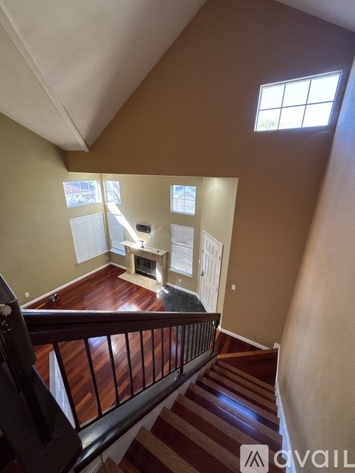 A living room with a fireplace and a staircase leading to the upper floor.