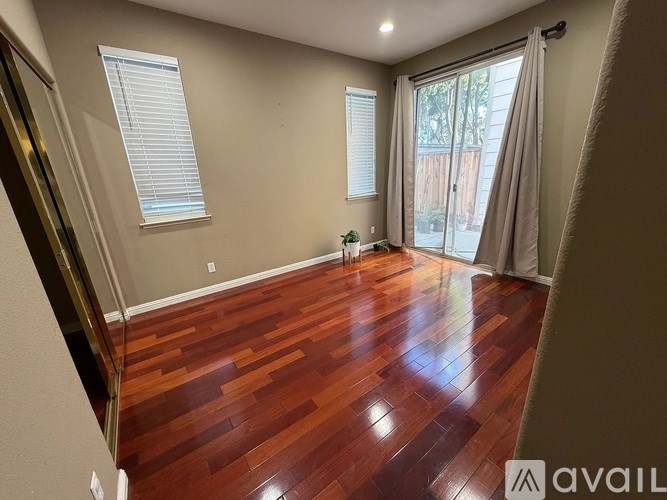 A room with wooden flooring and a sliding glass door.