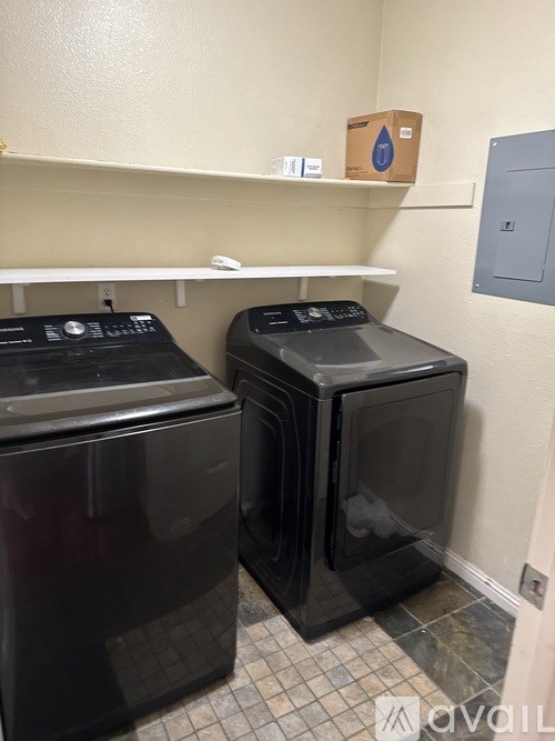 Two black washing machines in a small room.