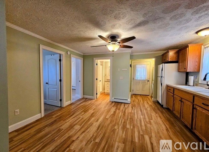 A kitchen with wooden floors and a ceiling fan.