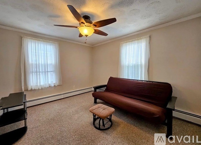 A living room with a brown couch and a ceiling fan.
