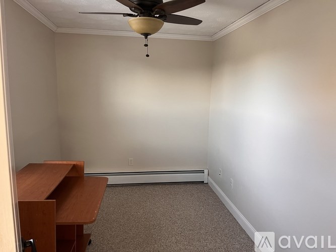 A room with a ceiling fan and a desk.