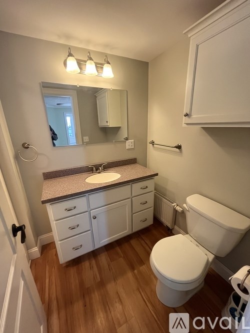 A bathroom with a toilet, sink, and mirror.