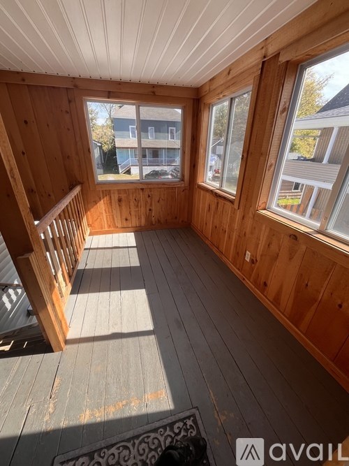 A wooden deck with a railing and a window overlooking a residential area.