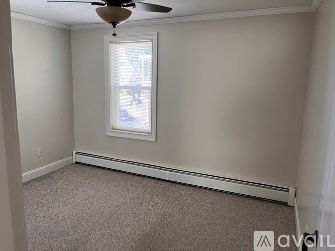 A room with a carpeted floor, a window with blinds, and a ceiling fan.