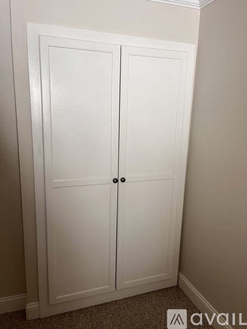 A white double door wardrobe with black handles.