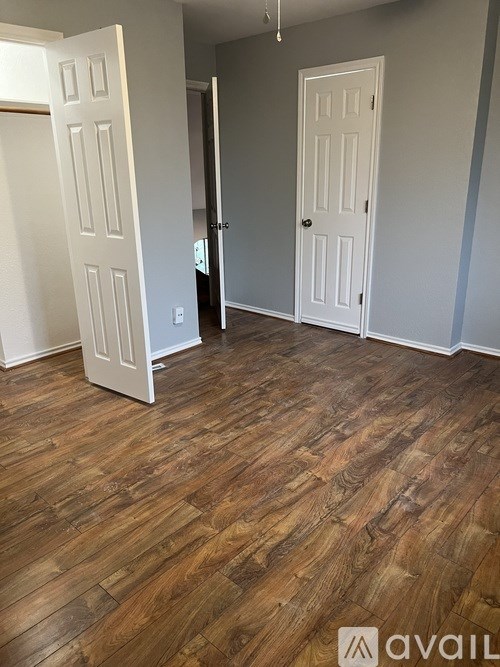 A room with two white doors and wooden flooring.