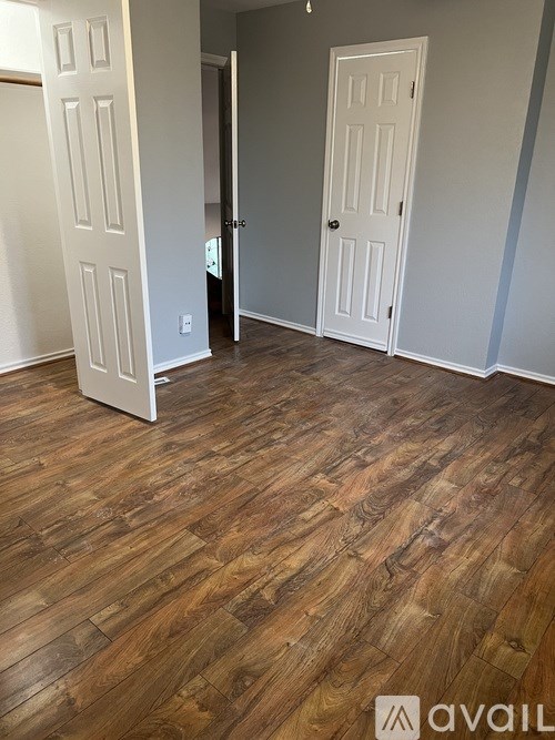 A room with wooden floors and two white doors.