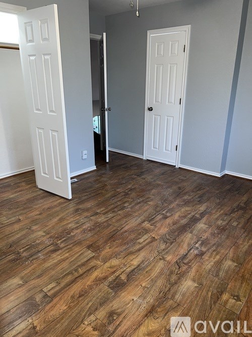 A room with wooden floors and two white doors.
