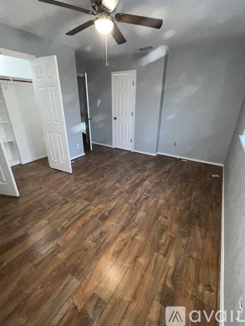 A room with a ceiling fan and wooden flooring.