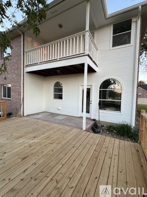 A white house with a balcony and a wooden deck.