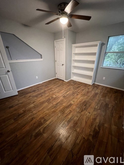 A room with wooden flooring and a ceiling fan.