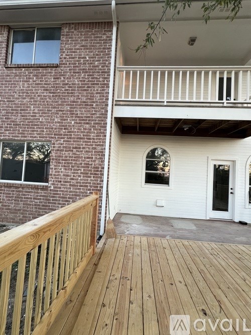 A balcony with a wooden railing and a brick building.