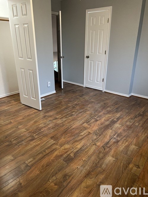 A room with wooden floors and two white doors.