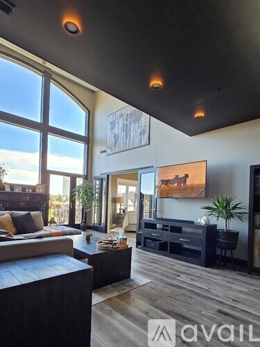 A living room with a large window and a painting of a horse on the wall.