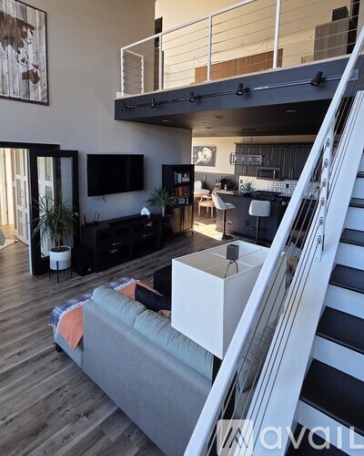 A living room with a grey couch and a staircase.
